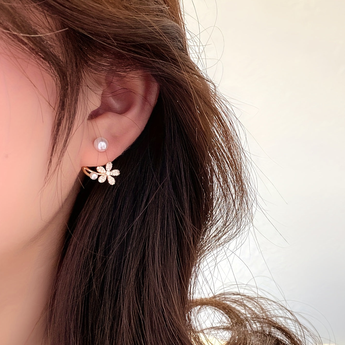 Brincos de pino com flor dourada requintada e decoração de pérola sintética com zircónias brilhantes. Joias elegantes e simples em liga metálica. Presente feminino moderno.