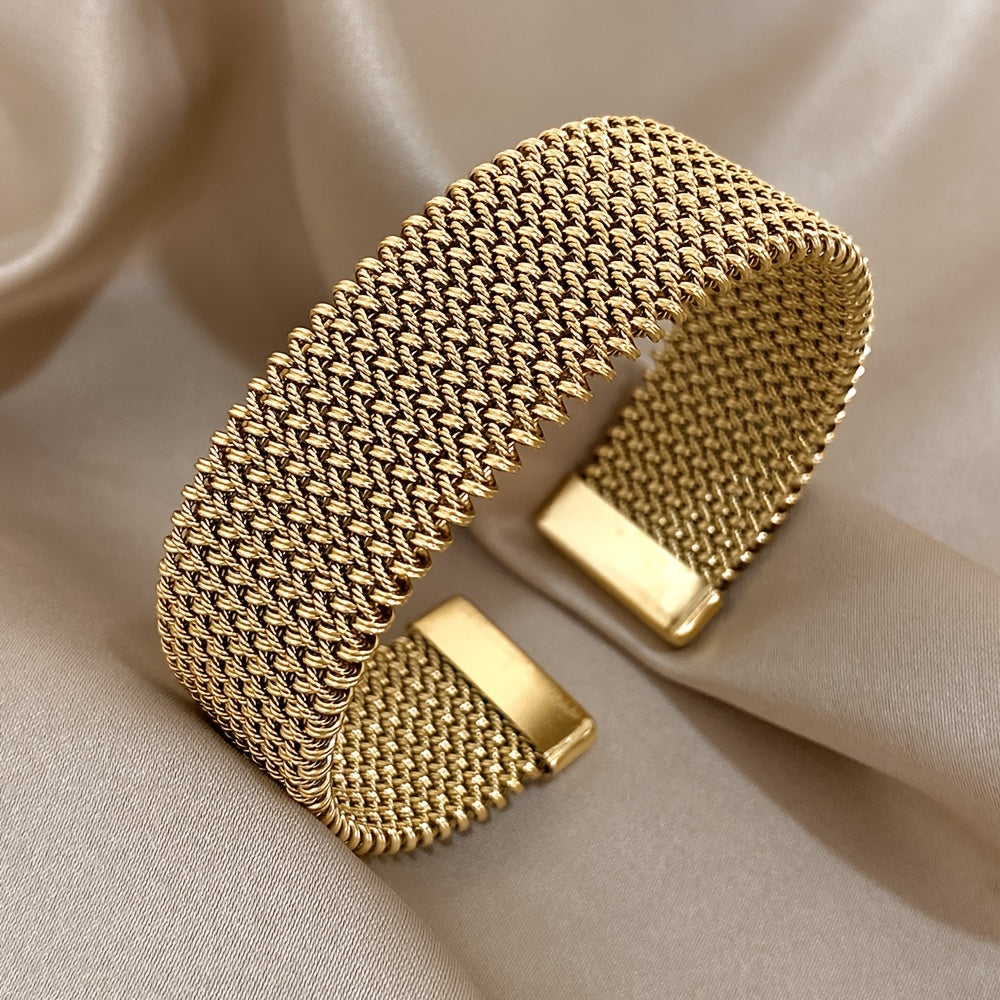 Nova bracelete moderna em aço inoxidável entrançado com um toque dourado. Acessório elegante num tom dourado versátil.