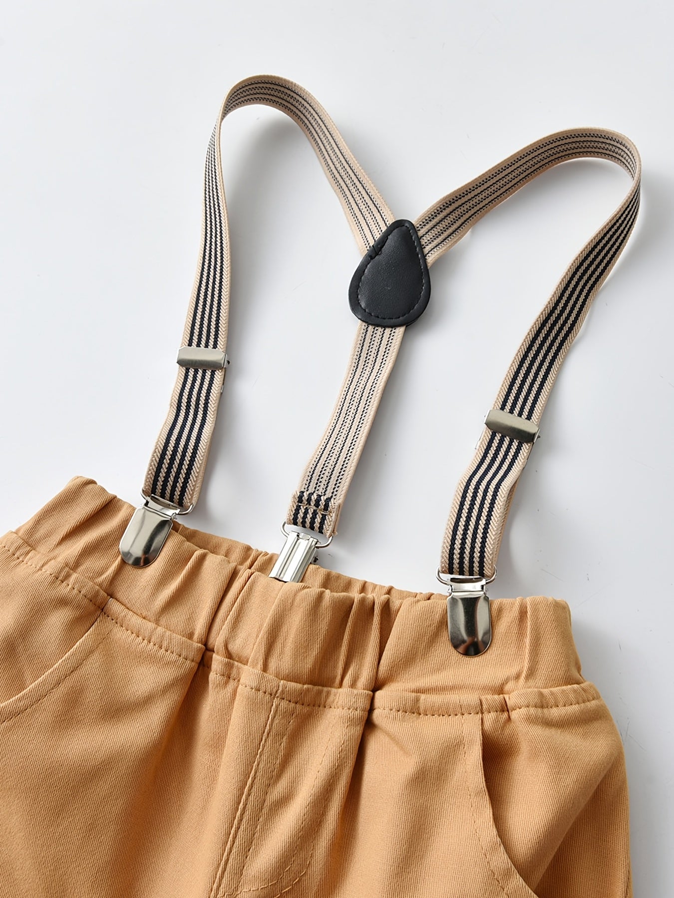 Conjunto de menino estilo cavalheiro, composto por camisa de manga comprida aos quadrados com botões e gravata borboleta, e calças com suspensórios. Ideal para uso diário e em atividades ao ar livre.